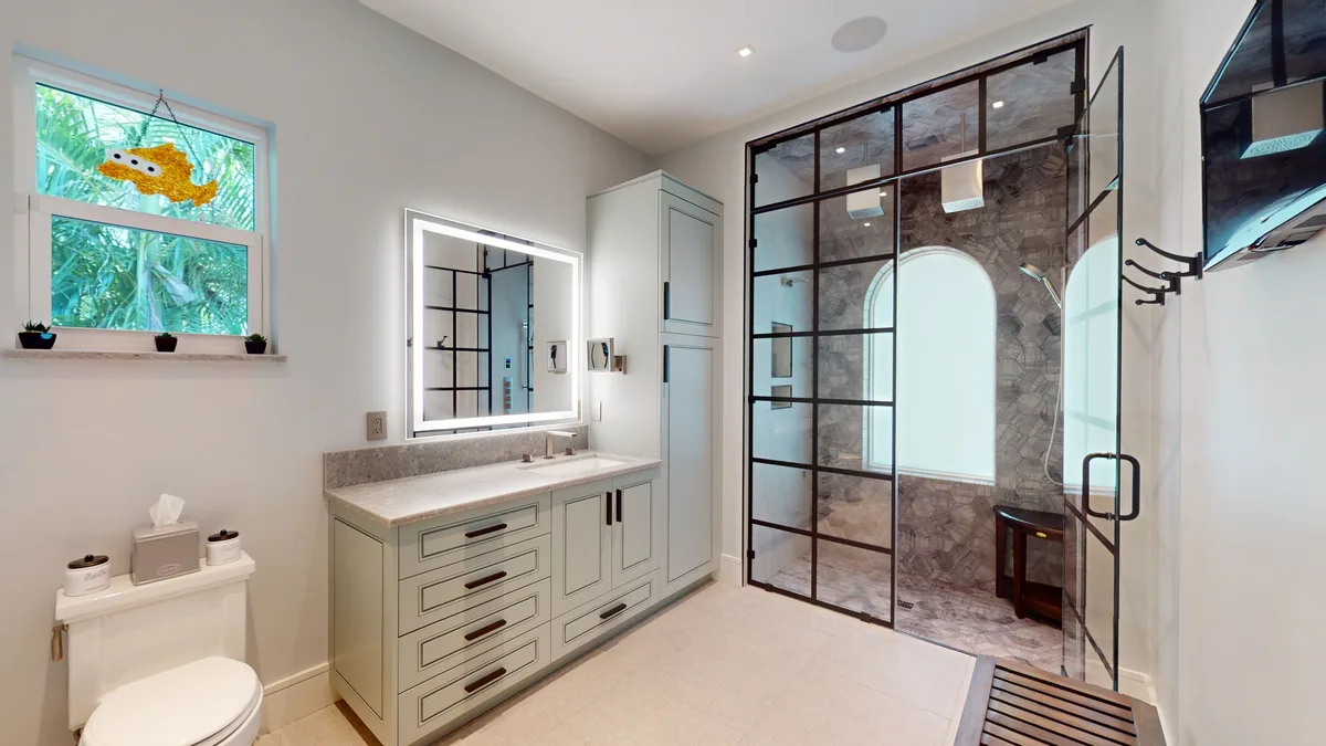 Completed bathroom suite with a floating vanity, black-framed shower glass, and pale tile
