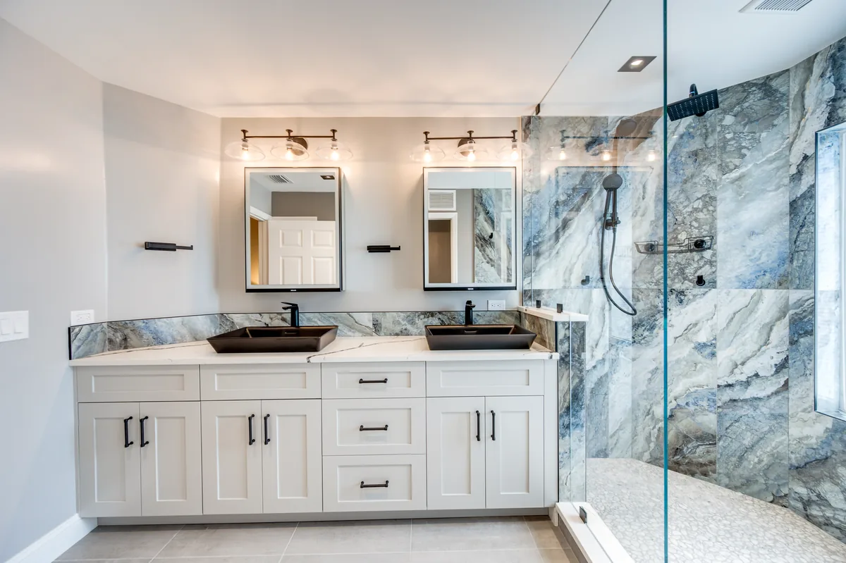 Completed bathroom with a blue marble-look shower, double vanity, and frameless glass