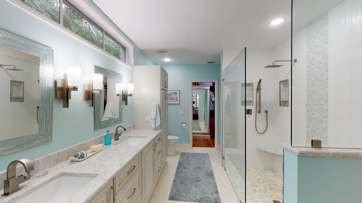 Completed bathroom with a sea-glass vanity wall, white cabinetry, and a walk-in shower