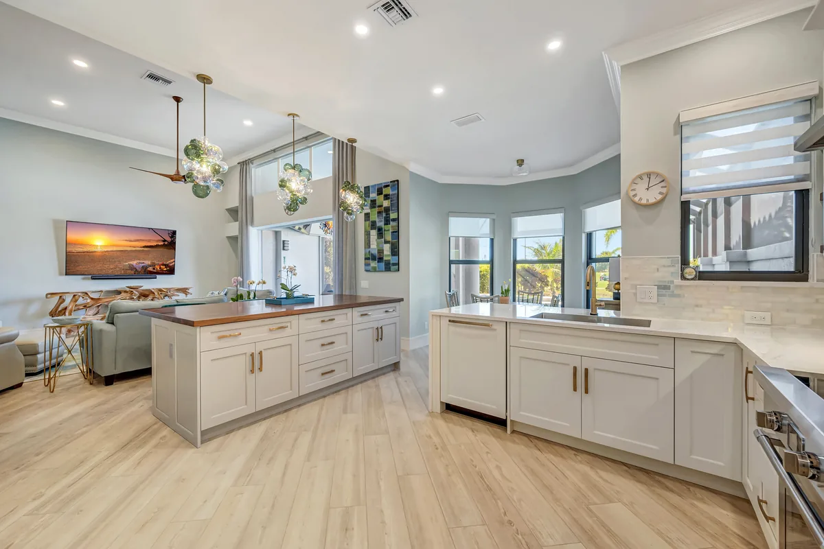 Completed open-plan kitchen with pale cabinetry, a large island, and warm wood flooring
