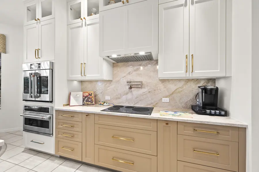 Two-tone coastal kitchen with a veined quartzite island, seafoam base cabinets and white uppers